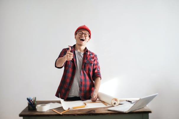 laughing-male-constructor-showing-thumb-up-at-working-desk-3760613